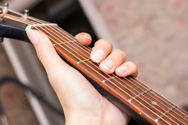 Fingers on the strings of black guitar