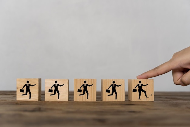 Fingers touching a wooden block depicts a businessman walking his career progression on a wooden block