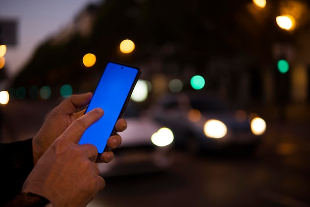 Fingers using cell phone screen outdoors at night