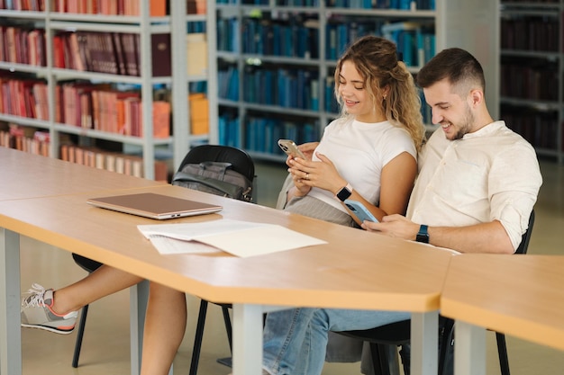 Finish of study in library Female close laptop and take smartphone to relax Man waiting girl Education concept