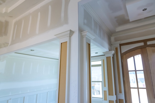 Finishing putty on drywall with a spatula the house on ceiling and wall