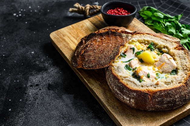 Finnish Creamy fish soup with salmon, trout, potatoes served in bread., top view