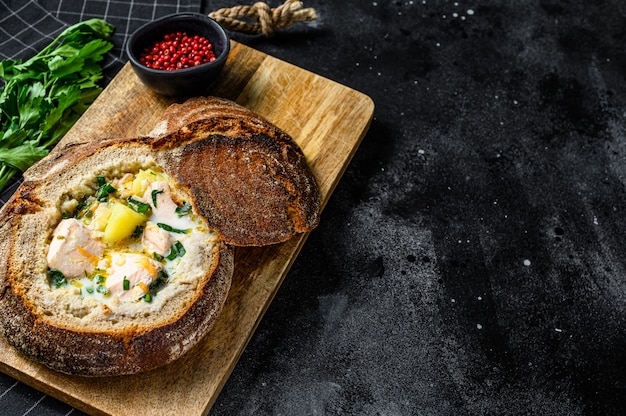 Finnish Creamy fish soup with salmon, trout, potatoes served in bread.