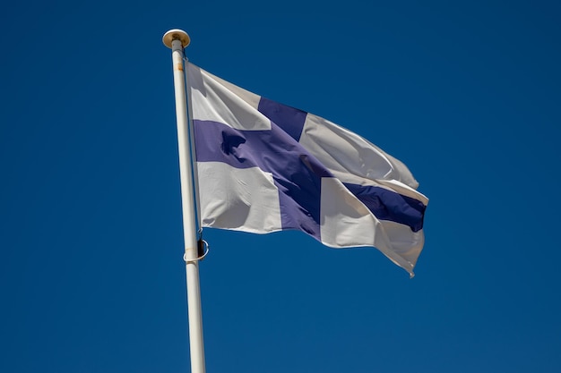 Finse vlag finse nationale vlag op de top van de mast in de wind en blauwe lucht