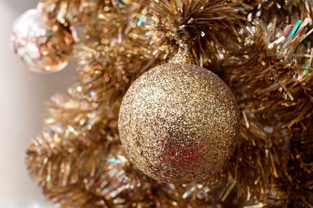 Fir branch with balls and festive lights on the christmas background with golden sparkles