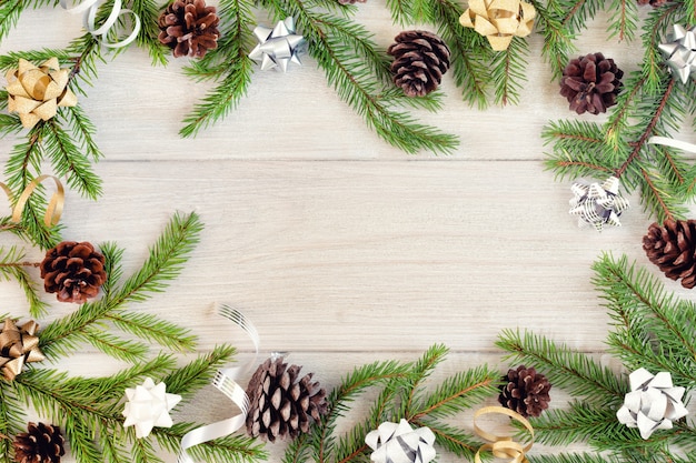 Fir branches are arranged in a circle on a light wooden background.