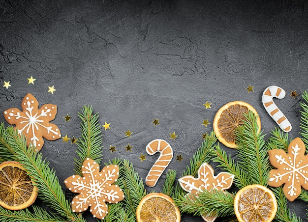 Fir branches, gingerbread, orange and confetti on a dark background