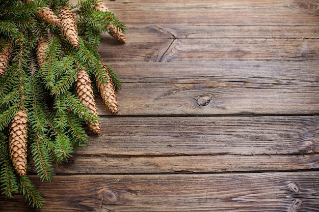 Fir branches with cones on brown wooden background