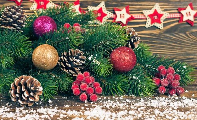 Fir kerstboom met decoratie op bruin houten achtergrond met sneeuwvlokken en garland.
