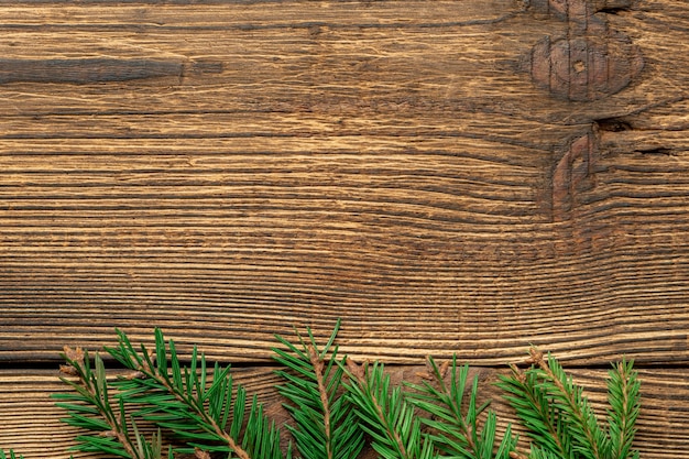 Fir, spruce branches on brown wooden with copy space