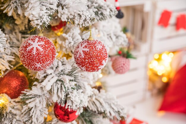 Fir tree background and festive decorations with snow blurred sparking glowing Happy New Yearholidays decoration red and white baubles hanging on a Christmas tree