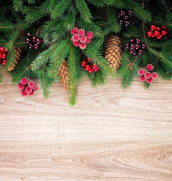 Fir tree border with cones and berries on wooden background with copy space, retro toned