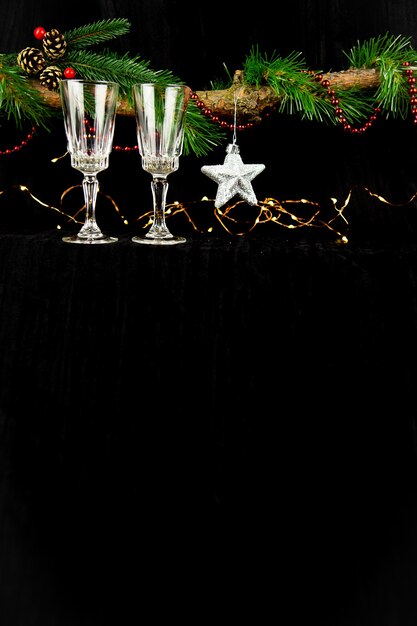 fir tree branch decorated with christmas lights, silver star and champagne glasses