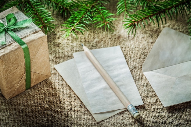 Fir tree branch handmade gift box paper pencil on sacking background.