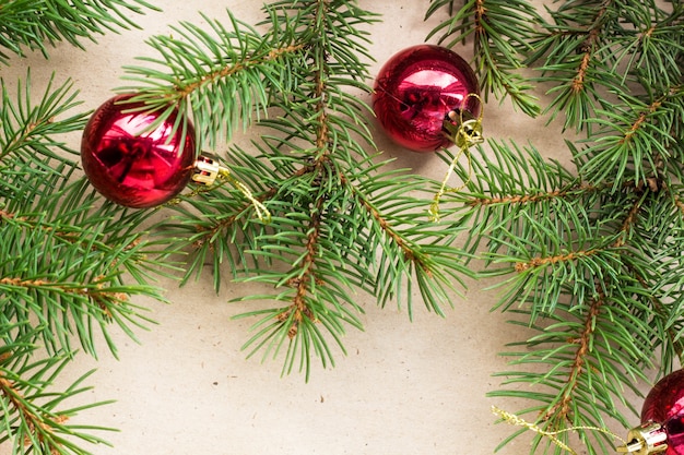 Fir tree branches decorated with red christmas balls as border on a rustic holiday background frame with copy space.