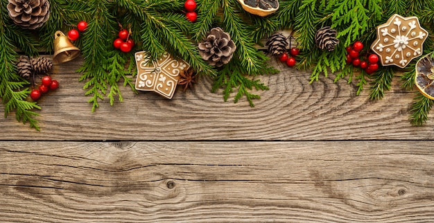 Fir tree branches with christmas decorations on wooden background. Christmas banner, border. Top view