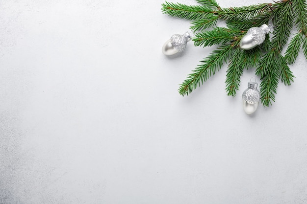 Fir tree branches with silver decorative acorns on stone background