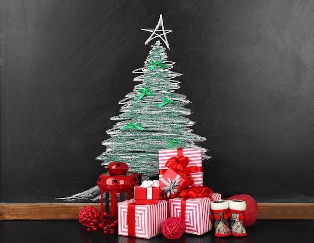 Fir tree drawing on blackboard and beautiful gifts. Xmas background