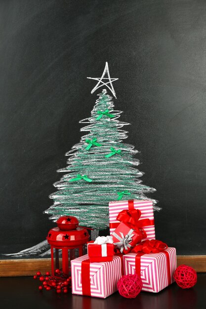 Fir tree drawing on blackboard and beautiful gifts. Xmas surface