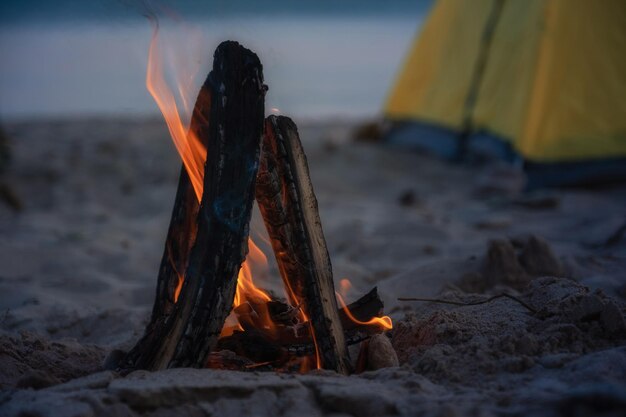 Fuoco in falò in spiaggia campeggio e tende per viaggiare