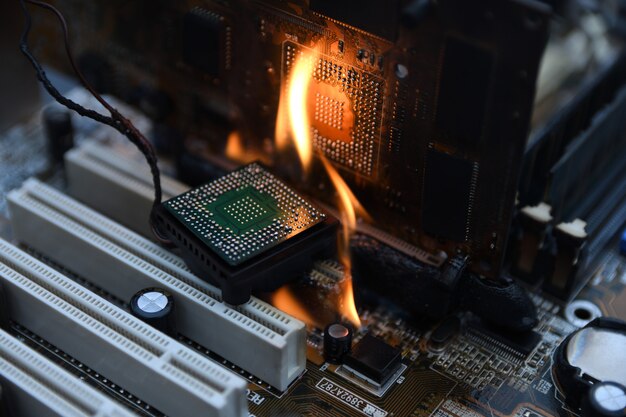 火の燃える、燃えるコンピューターのマザーボード、CPU、GPU、ビデオカード、電子回路基板上のプロセッサ