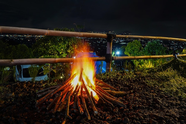 A fire burns in front of a fence at night