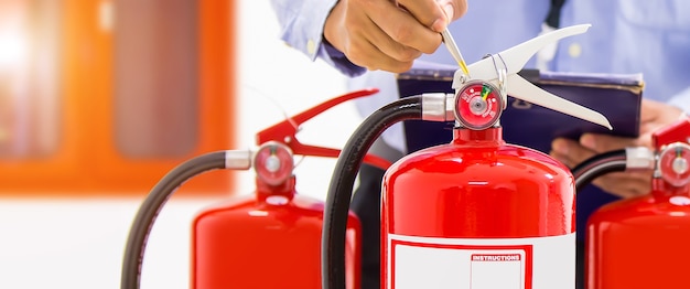 Photo fire engineering checking pressure gauge level of fire extinguisher.