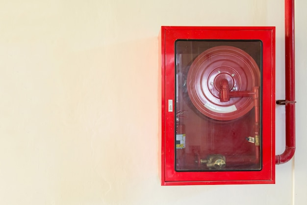 Fire extinguisher and fire hose reel on concrete wall