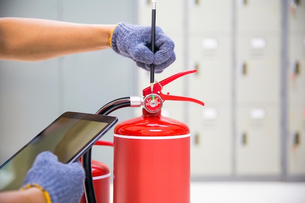 Fire extinguisher has hand engineer inspection checking\
pressure gauges to prepare fire equipment for protection and\
prevent emergency and safety rescue and alarm system training\
concept