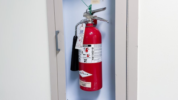 A fire extinguisher is hanging on a blue wall.