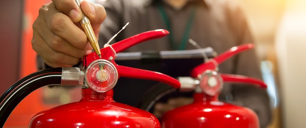 Foto il vigile del fuoco sta controllando il manometro del serbatoio rosso degli estintori