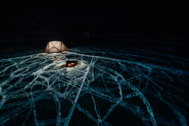 Fire on ice at night Campground on ice Tent stands next to bonfire Lake Baikal