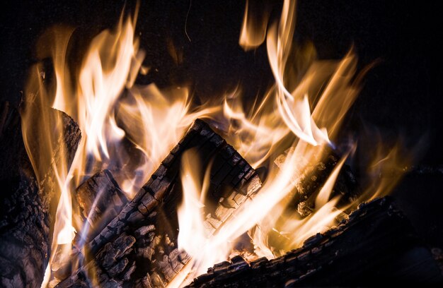 Lingue di fuoco arancione su sfondo nero in un camino in mattoni