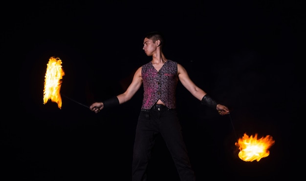 Fire performer man perform burning poi spinning in darkness outdoors performing