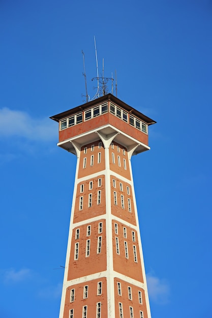 Fire tower against the blue sky with clouds.