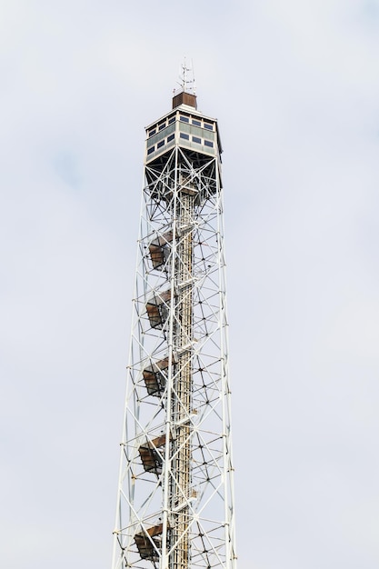 A fire watch tower with a wooden house on top of it against a light blue sky background with white c