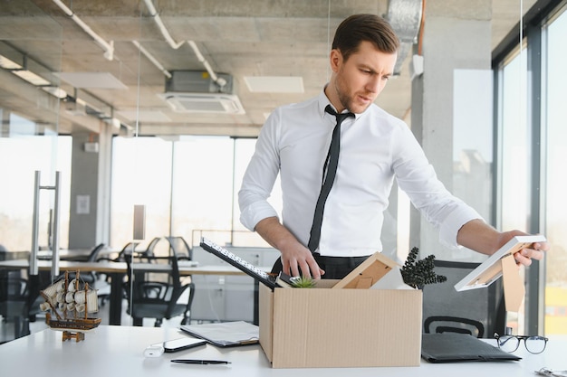 Photo fired young man packing his stuff in office