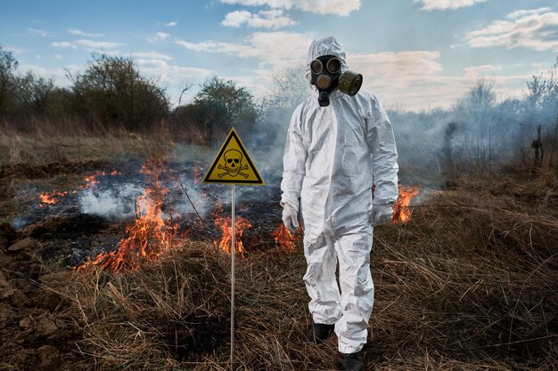 Пожарный-эколог в газовой маске, работающий в поле с лесным пожаром