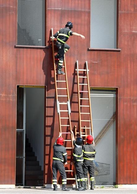 firefighter enters in the house with a wooden ladd