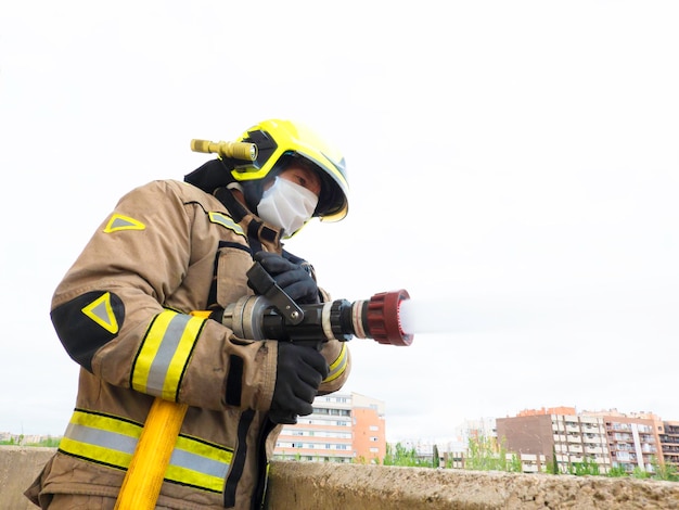 Firefighter equipped with mask and intervention suit throws water from a balcony