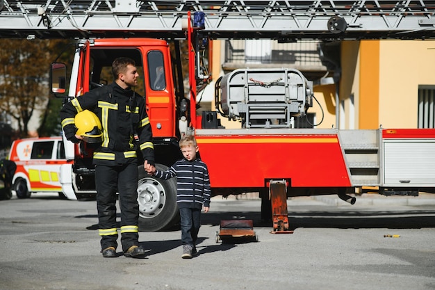 火と煙で彼を救うために子供の男の子を保持している消防士消防士は火から男の子を救助します