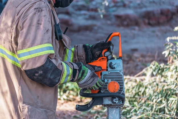 Firefighter starting chainsaw, in rescue.