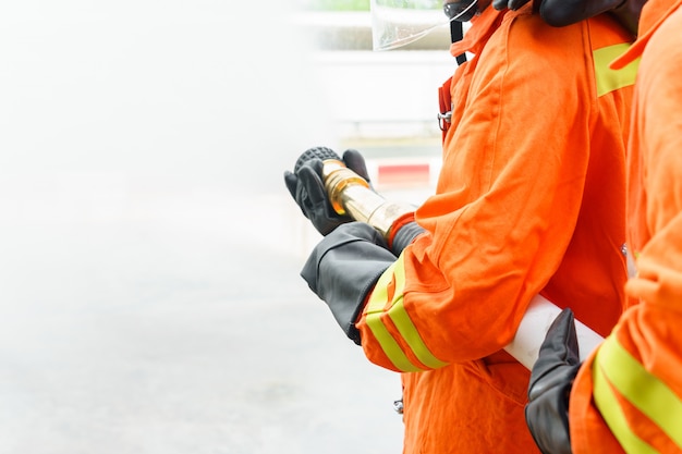 Firefighter using extinguisher and water from hose for fire fighting