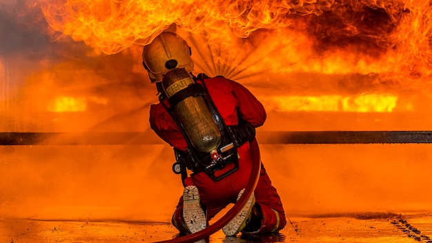 Firefighter using extinguisher and water from hose for fire fighting