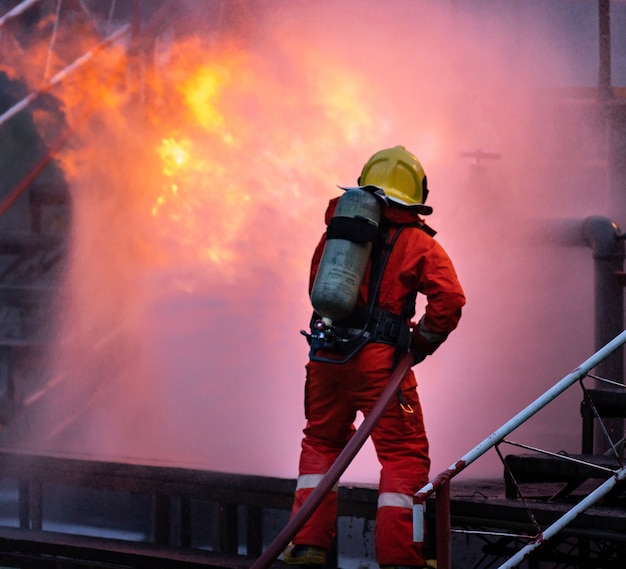 Vigile del fuoco che utilizza un estintore a nebbia d'acqua per combattere con la fiamma del fuoco