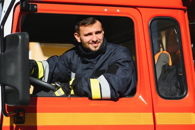 Foto il vigile del fuoco al volante di un veicolo di emergenza si reca sul luogo dell'azione e spegne l'incendio