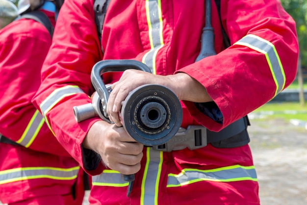 Foto vigili del fuoco in tuta antincendio in possesso di un tubo dell'acqua all'aperto