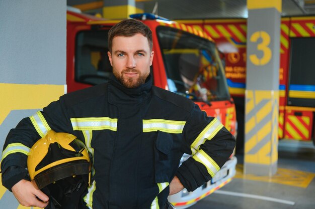 Firefighters man in a protective suit near fire truck Protection rescue from danger Fire station