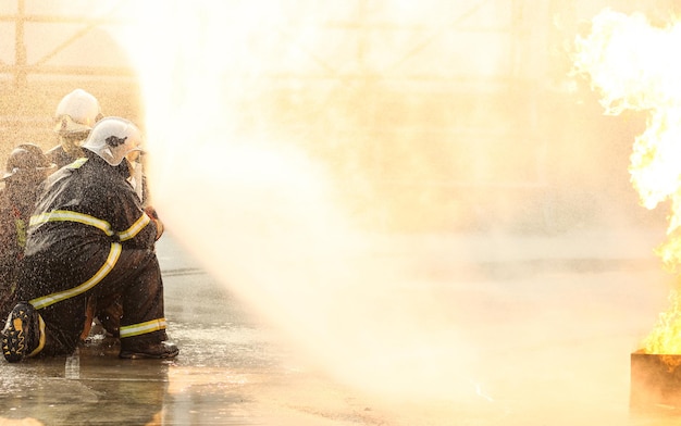 Firefighters using Twirl water fog type fire extinguisher to fighting with the fire flame from oil to control fire not to spreading out Firefighter and industrial safety concept