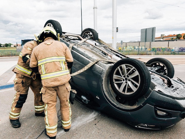 Firefighters work in traffic accident car overturned on public\
road